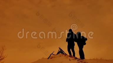 两位游客站在一座山上。 游客攀登一座阳光剪影山